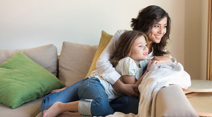 mom and daughter on couch looking out window